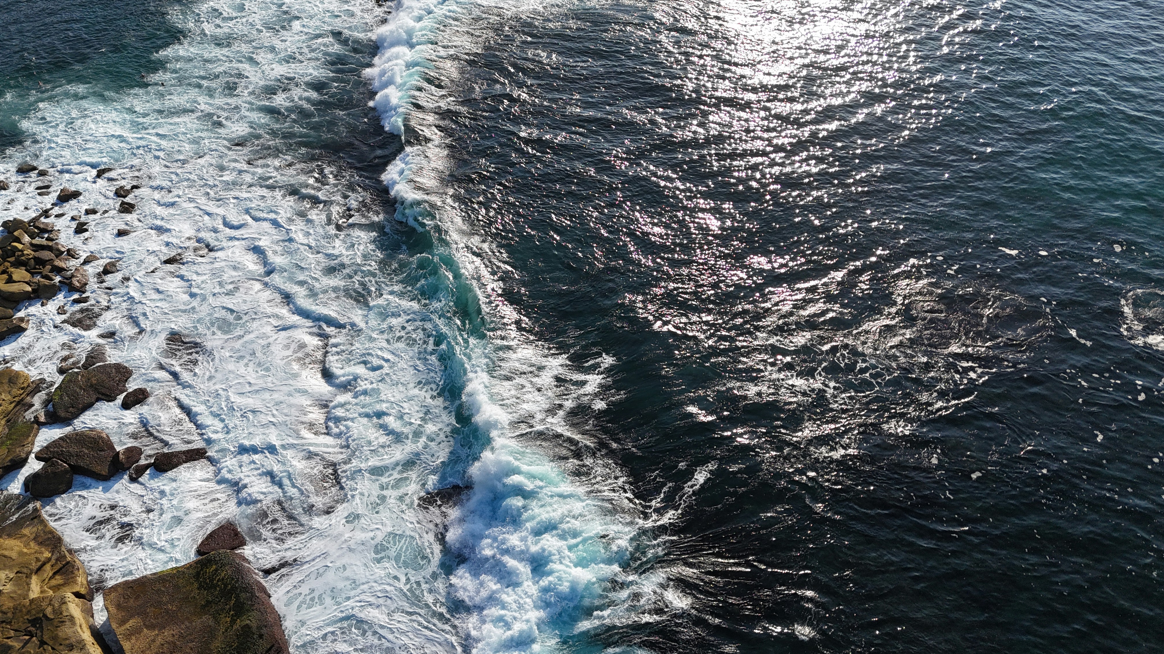 An aerial view of the ocean with a boat in the water