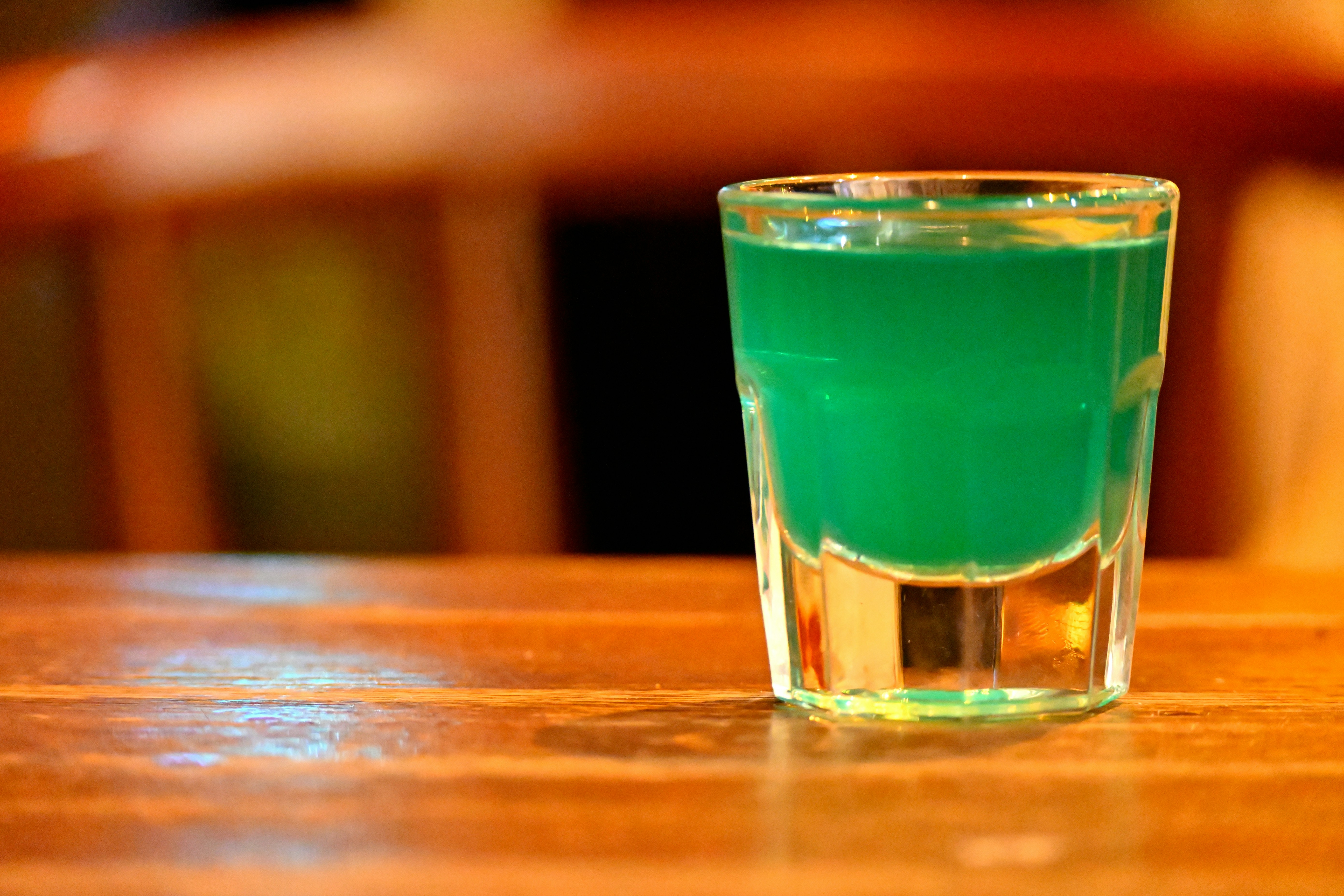 A glass of green liquid sitting on top of a wooden table