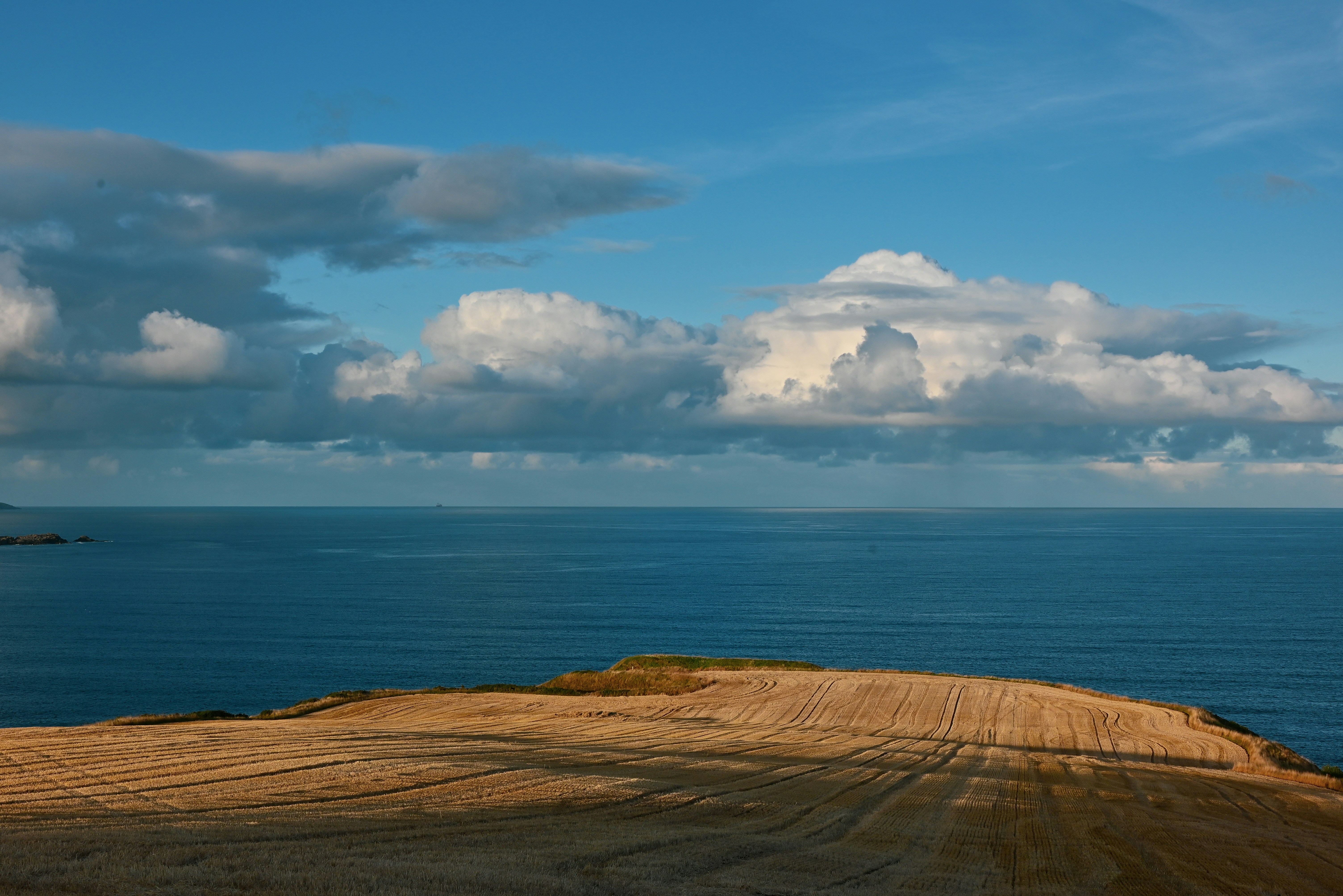 A dirt road near the ocean under a cloudy sky