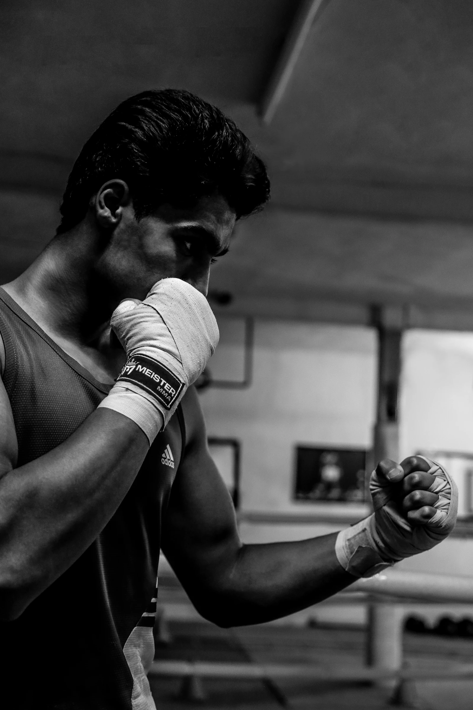 A black-and-white portrait of a boxer with wrapped hands