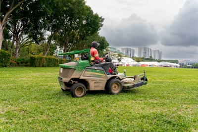 A man riding on the back of a green lawn mower