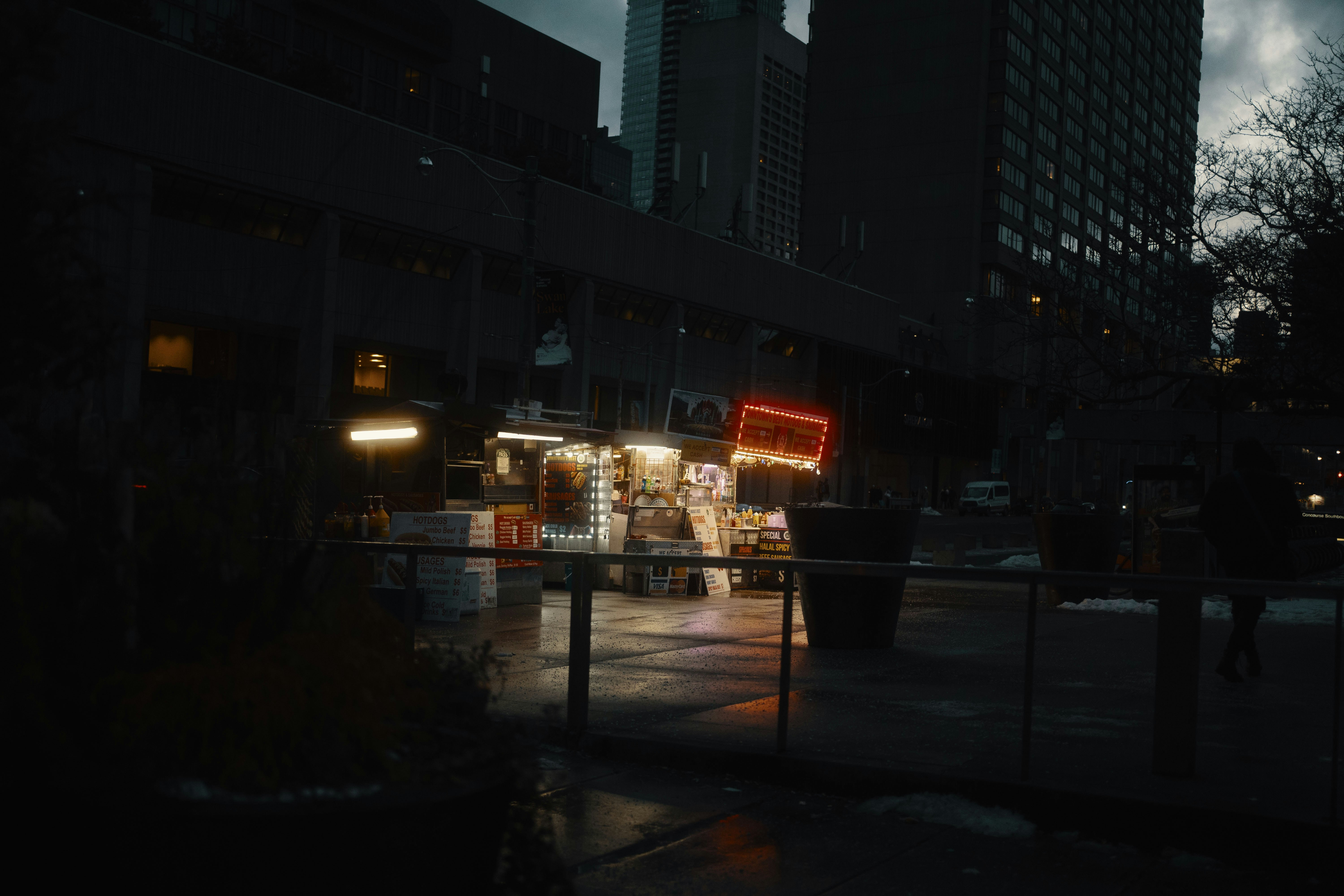 A city street at night with tall buildings photo – Free Car Image on ...