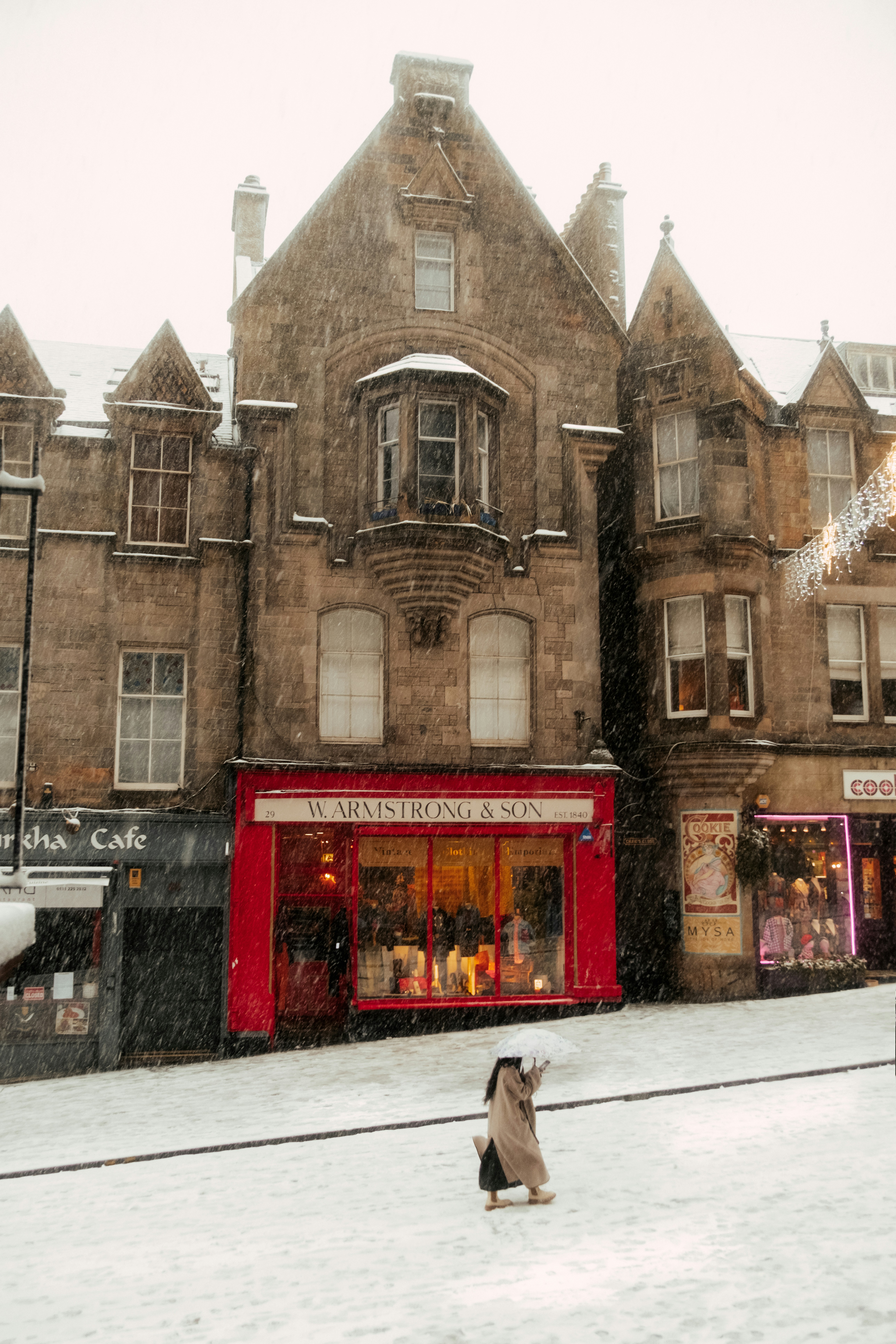 A dog is sitting in the snow in front of a building