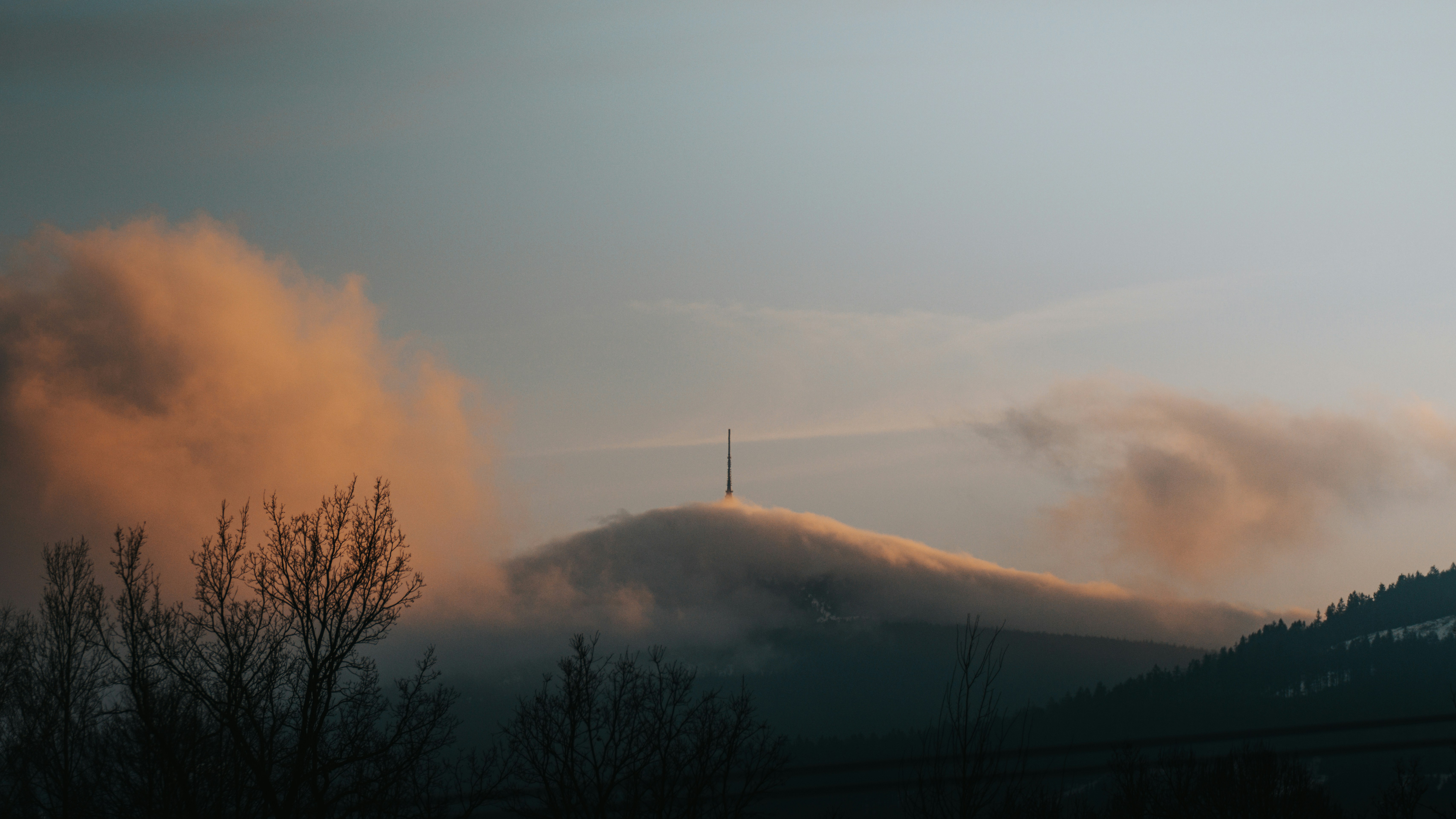 A view of a mountain with clouds in the sky