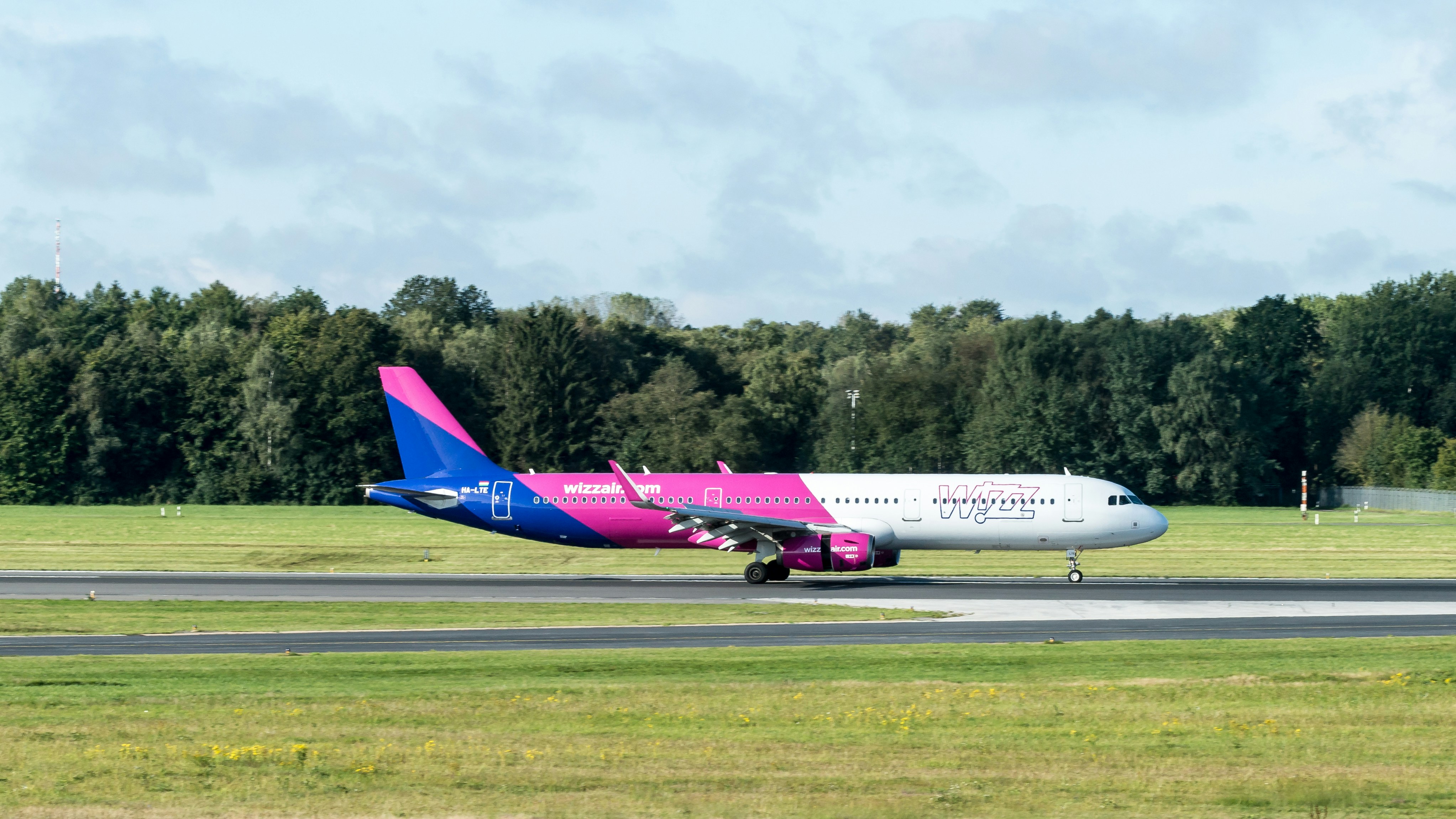 A pink and blue plane is on the runway