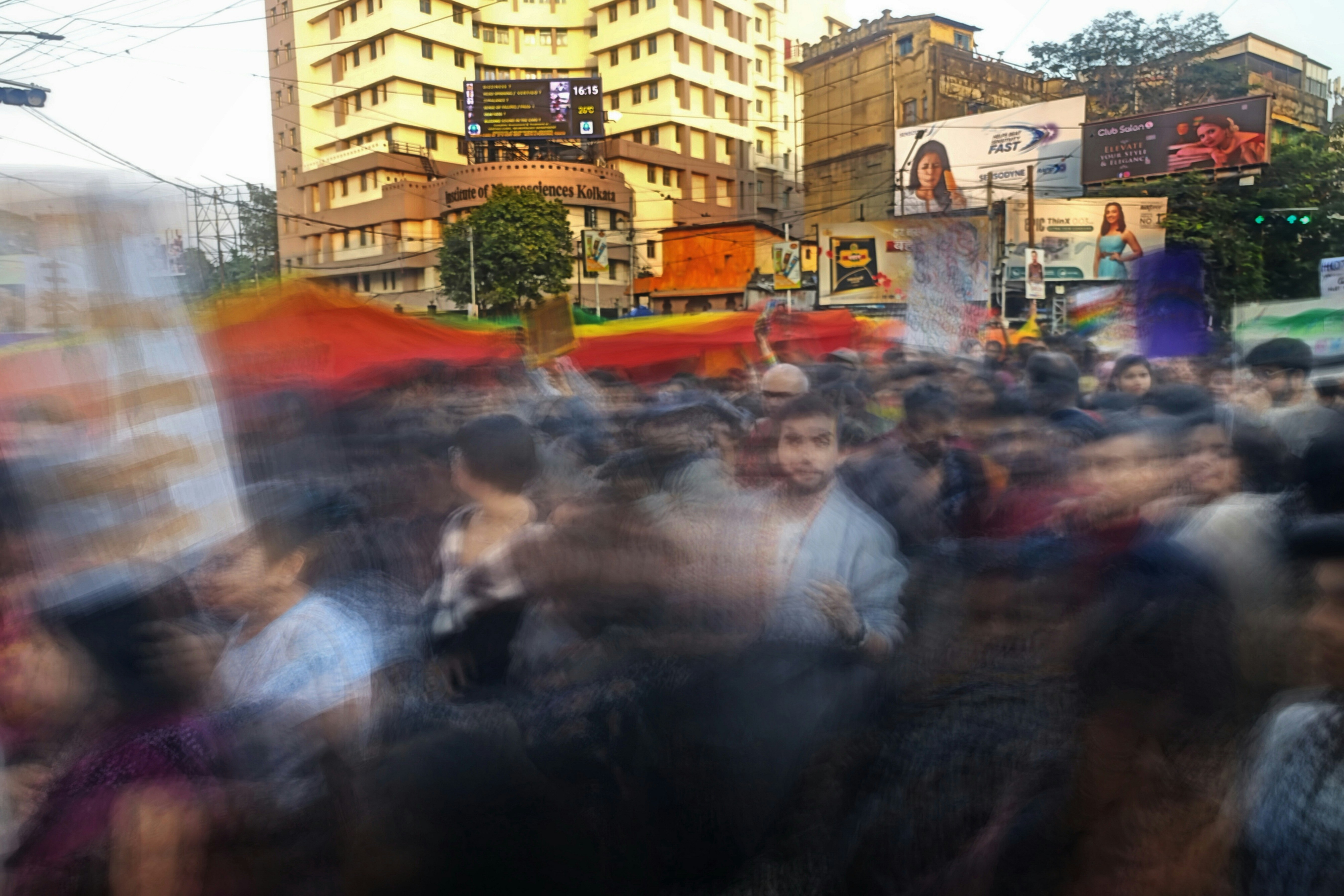 A crowd of people walking down a street next to tall buildings