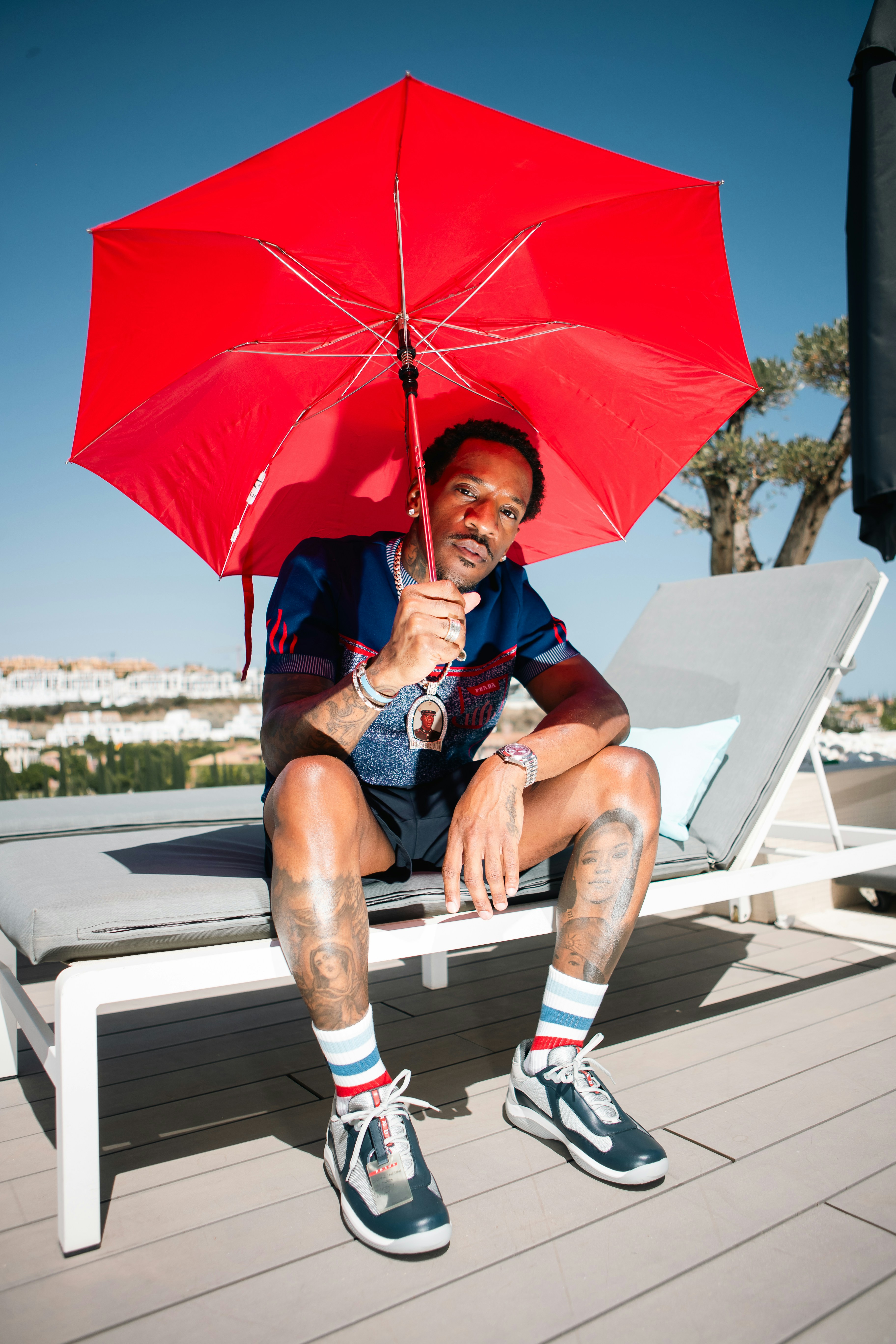 A man sitting on a bench holding a red umbrella
