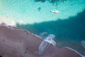 An aerial view of a beach with a boat in the water