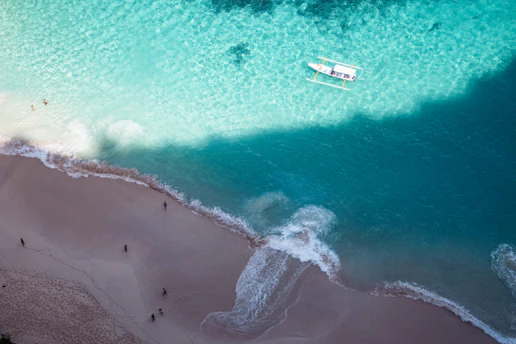 An aerial view of a beach with a boat in the water