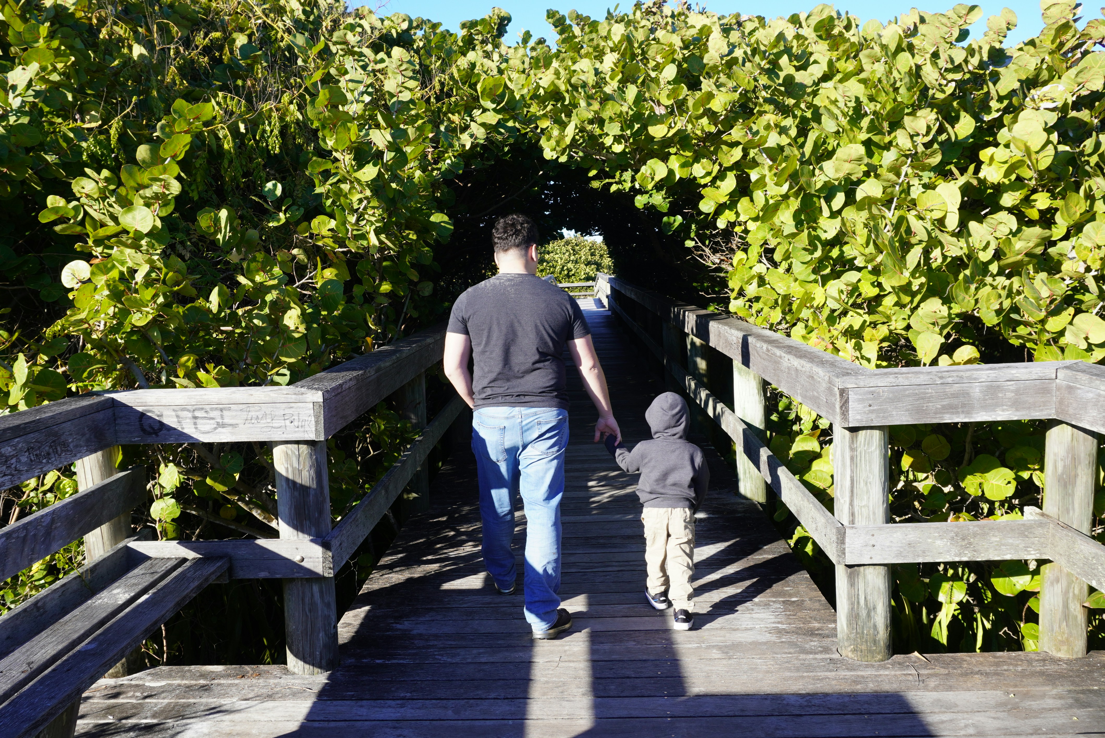 A man and a child walking up a wooden walkway