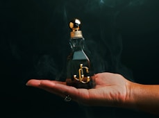 A person holding a small bottle with an anchor on it
