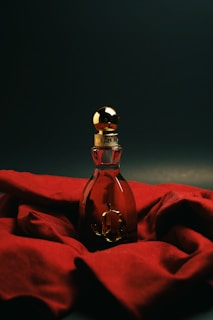 A bottle of perfume sitting on top of a red cloth