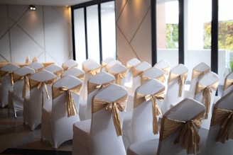 A room filled with white chairs covered in gold sashes