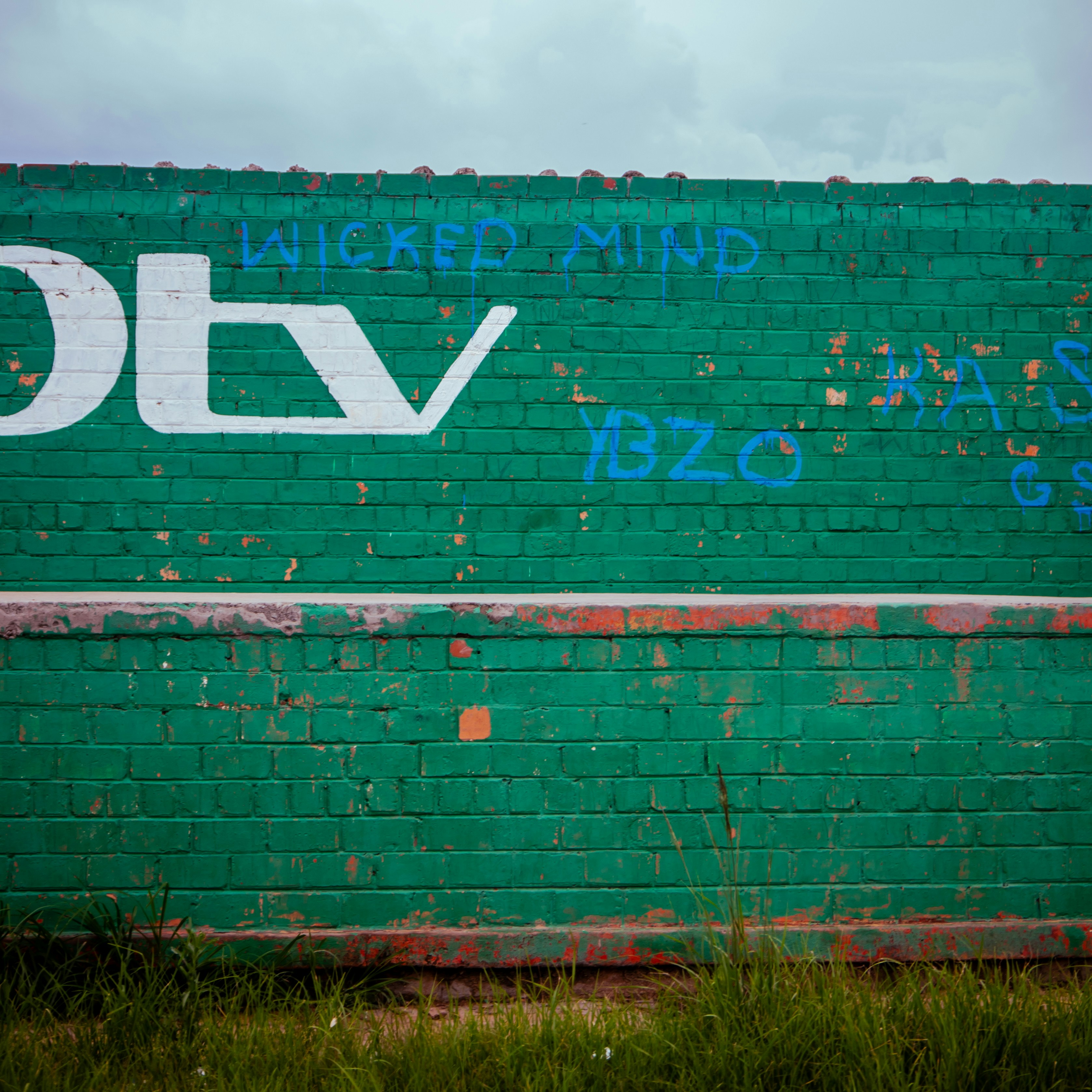 A green brick wall with graffiti on it