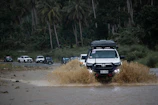 A white truck driving through a flooded street