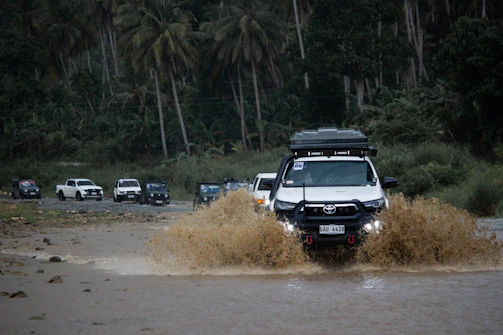 A white truck driving through a flooded street
