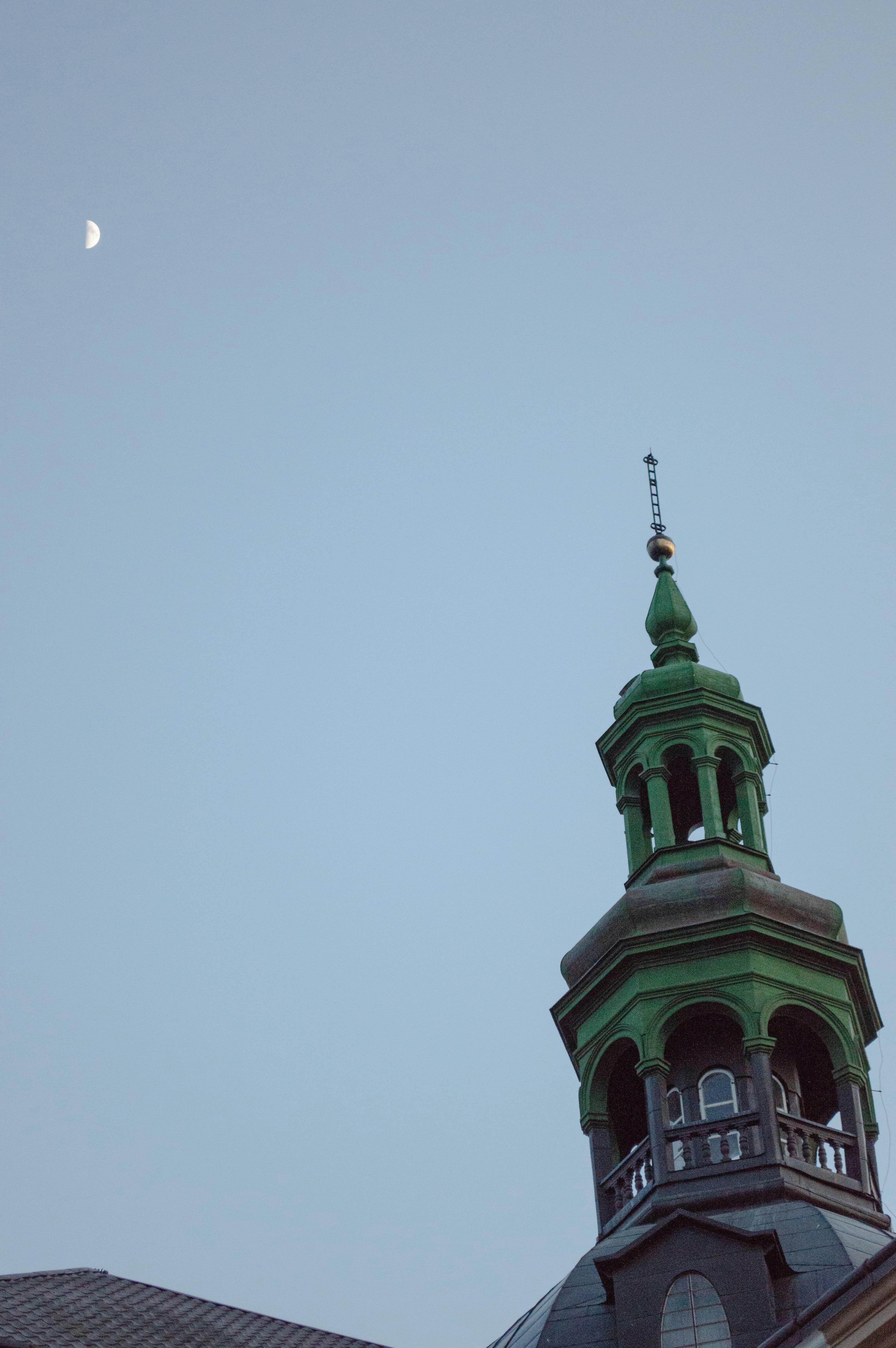 A clock tower with a half moon in the background