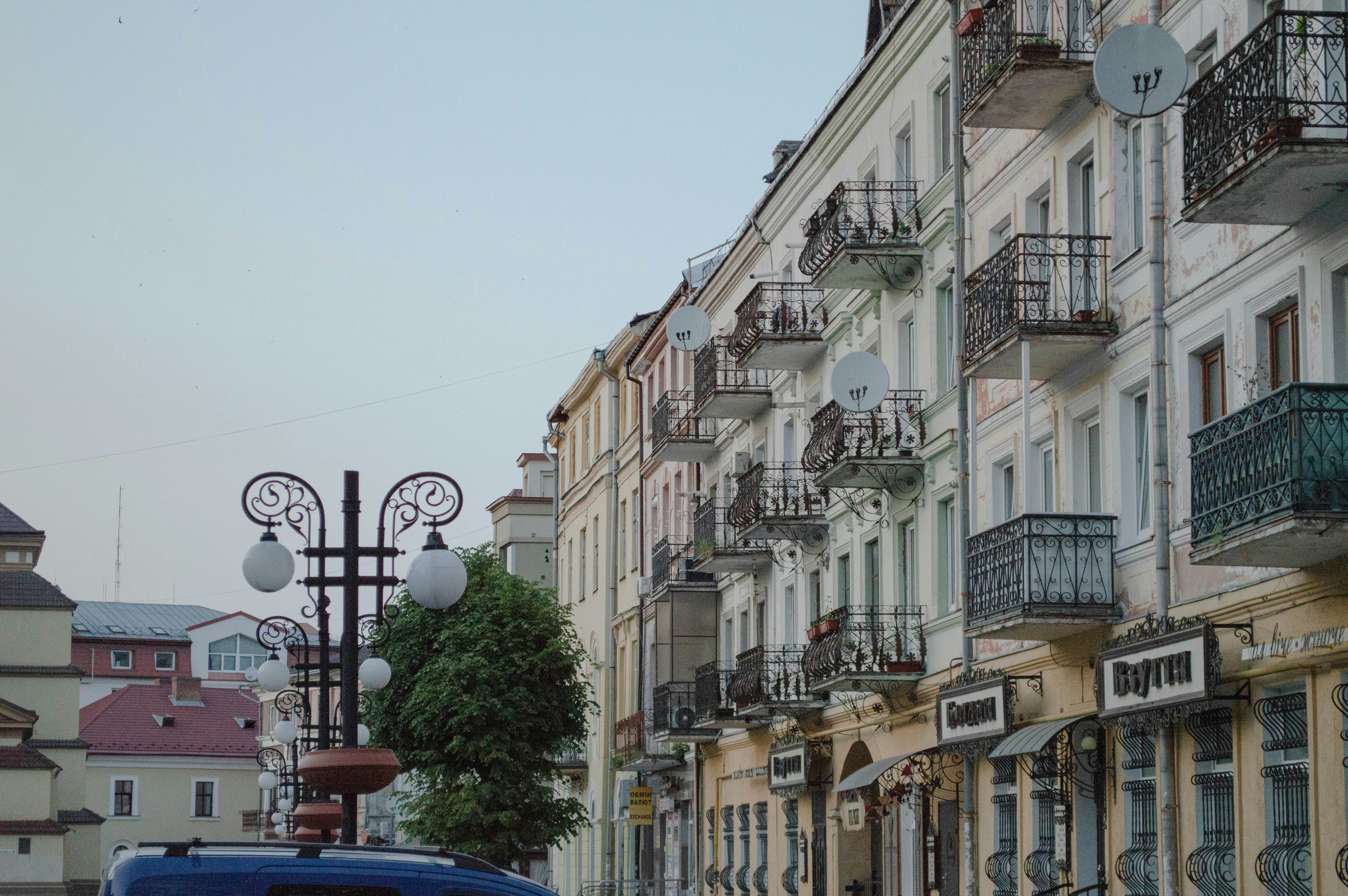 A blue car driving down a street next to tall buildings