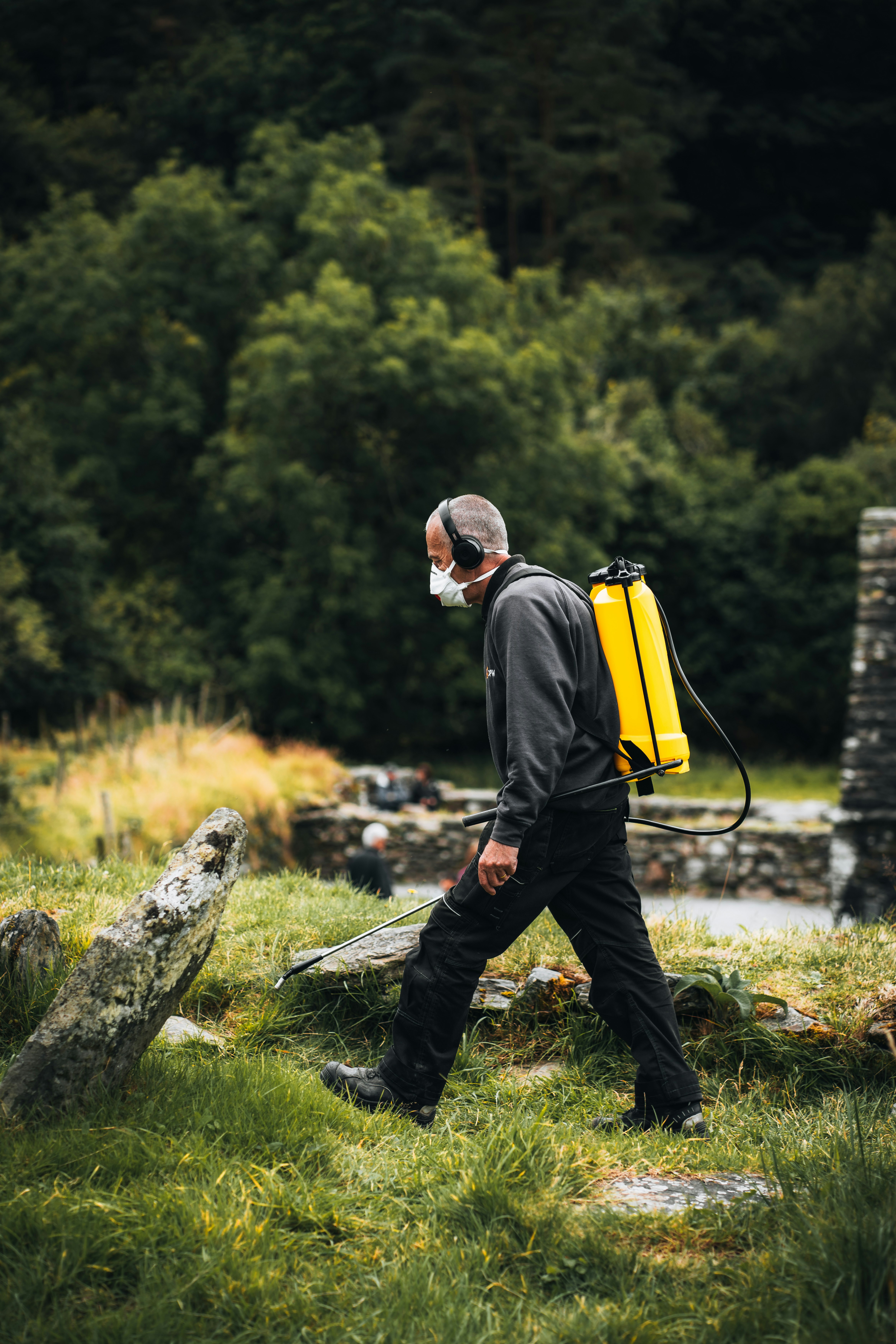 A man with a yellow backpack walking through a field