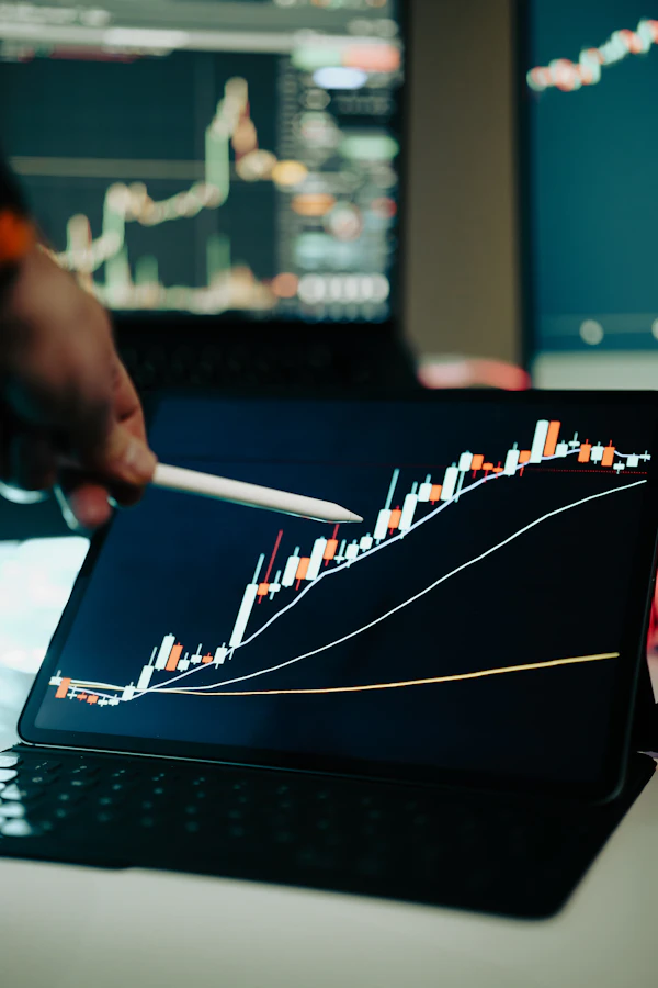 Mão apontando para um gráfico financeiro na tela de um notebook