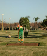 A man standing in a park with a shovel