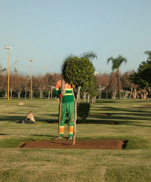 A man standing in a park with a shovel