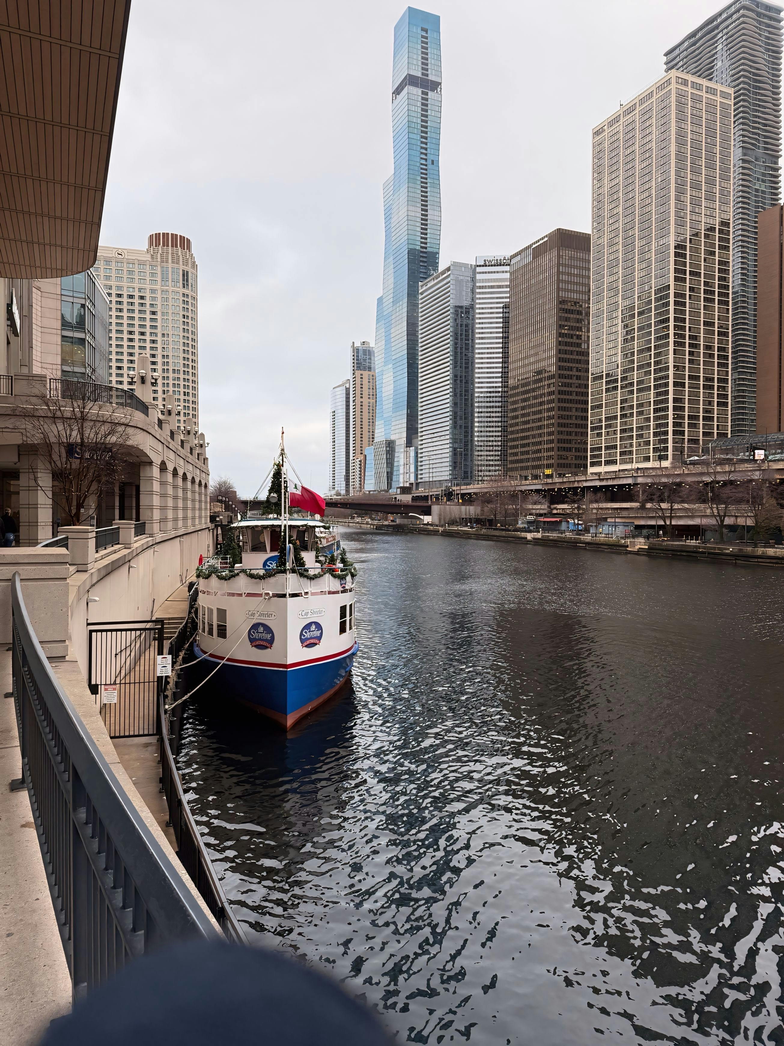 A boat traveling down a river next to tall buildings