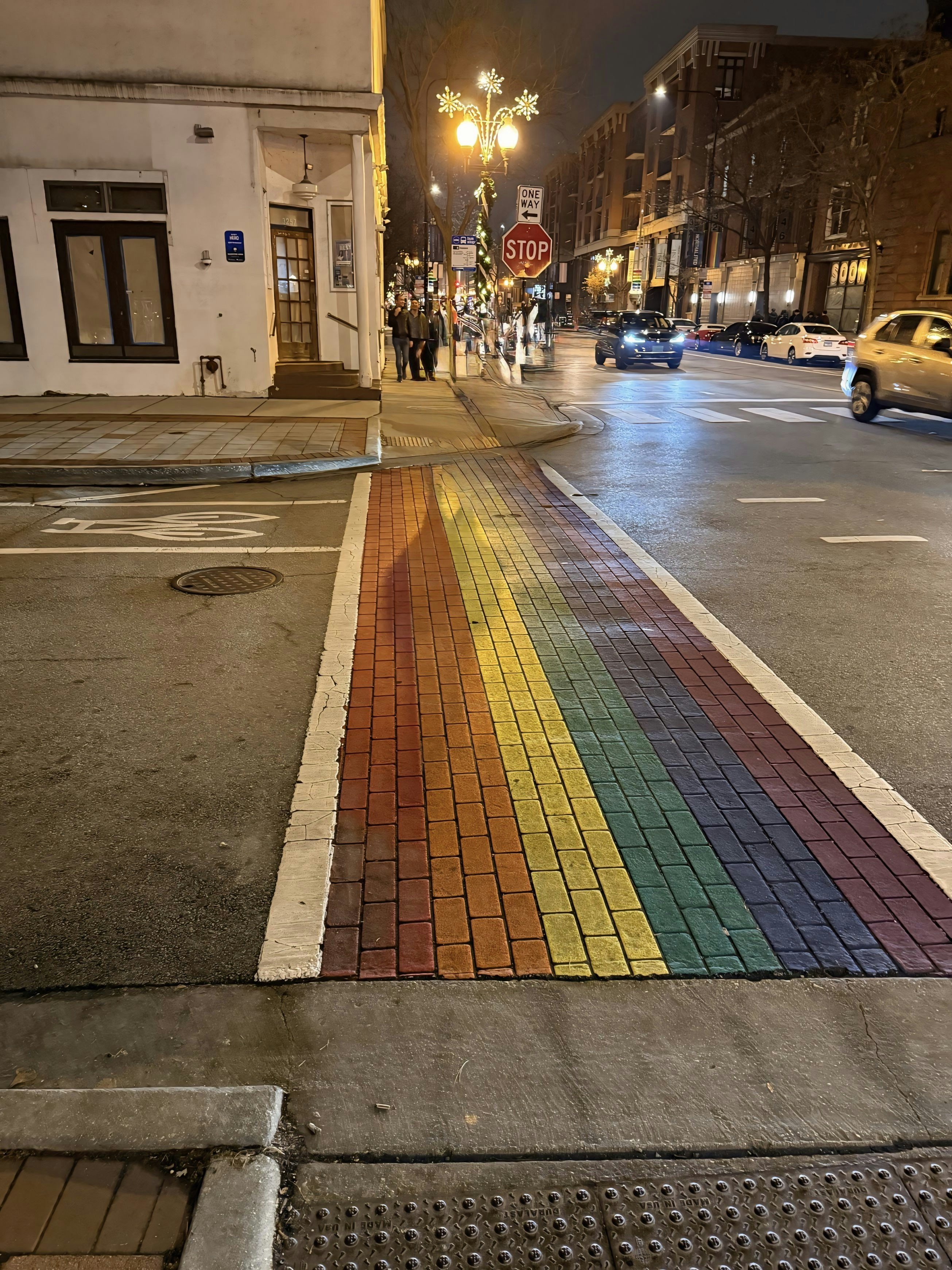 A rainbow painted sidewalk on a city street