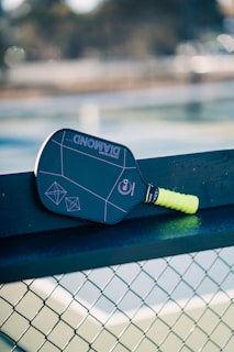 A tennis racket resting on a tennis net