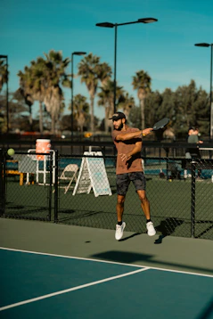 A man swinging a pickle ball racquet on a court