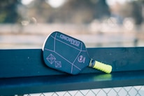 A close up of a tennis racket on a bench
