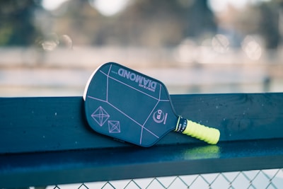 A close up of a tennis racket on a bench