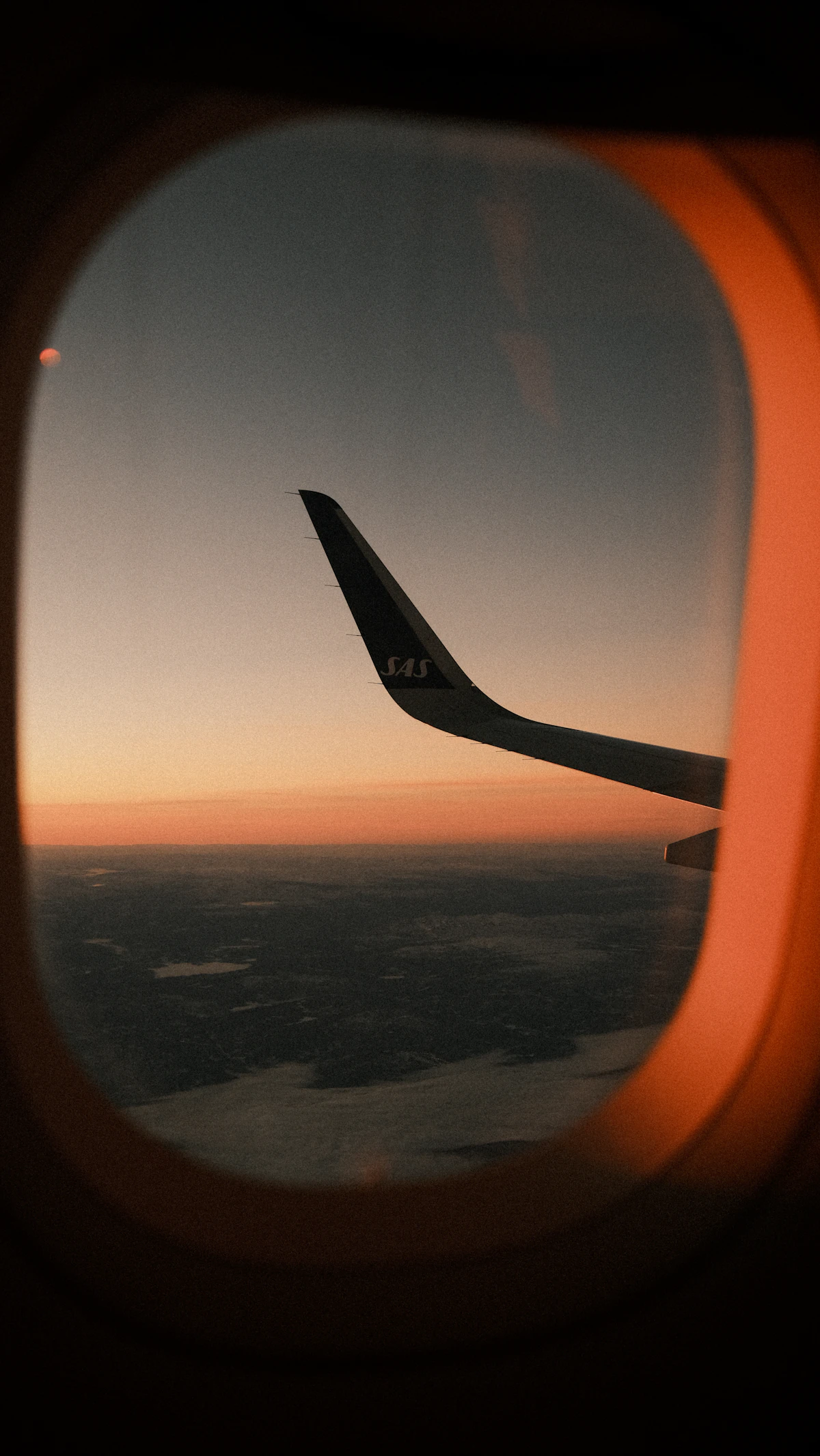 View of an airplane wing above the clouds during a flight at sunset