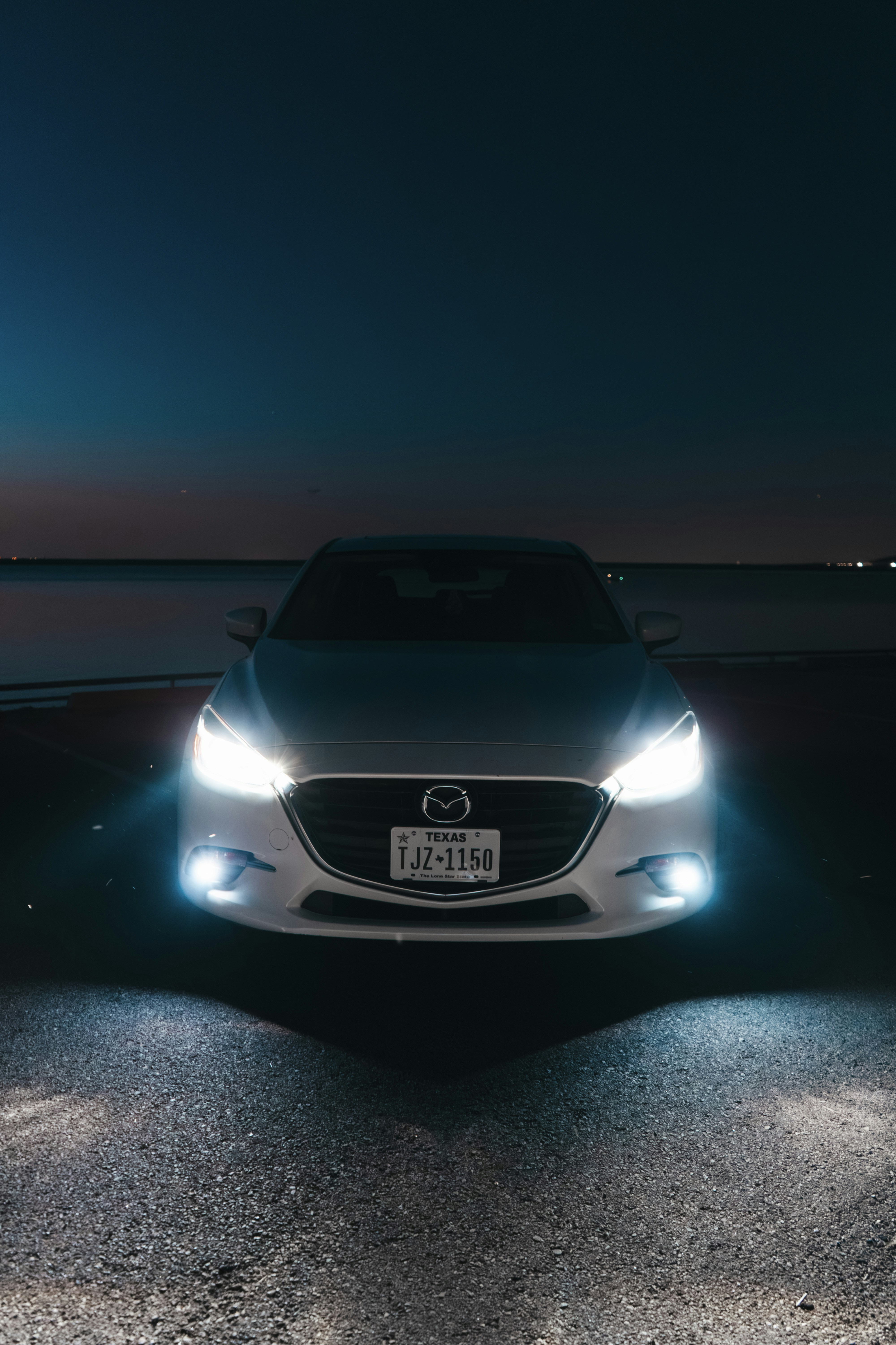 A white car parked on the side of a road at night