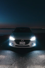 A white car parked on the side of a road at night
