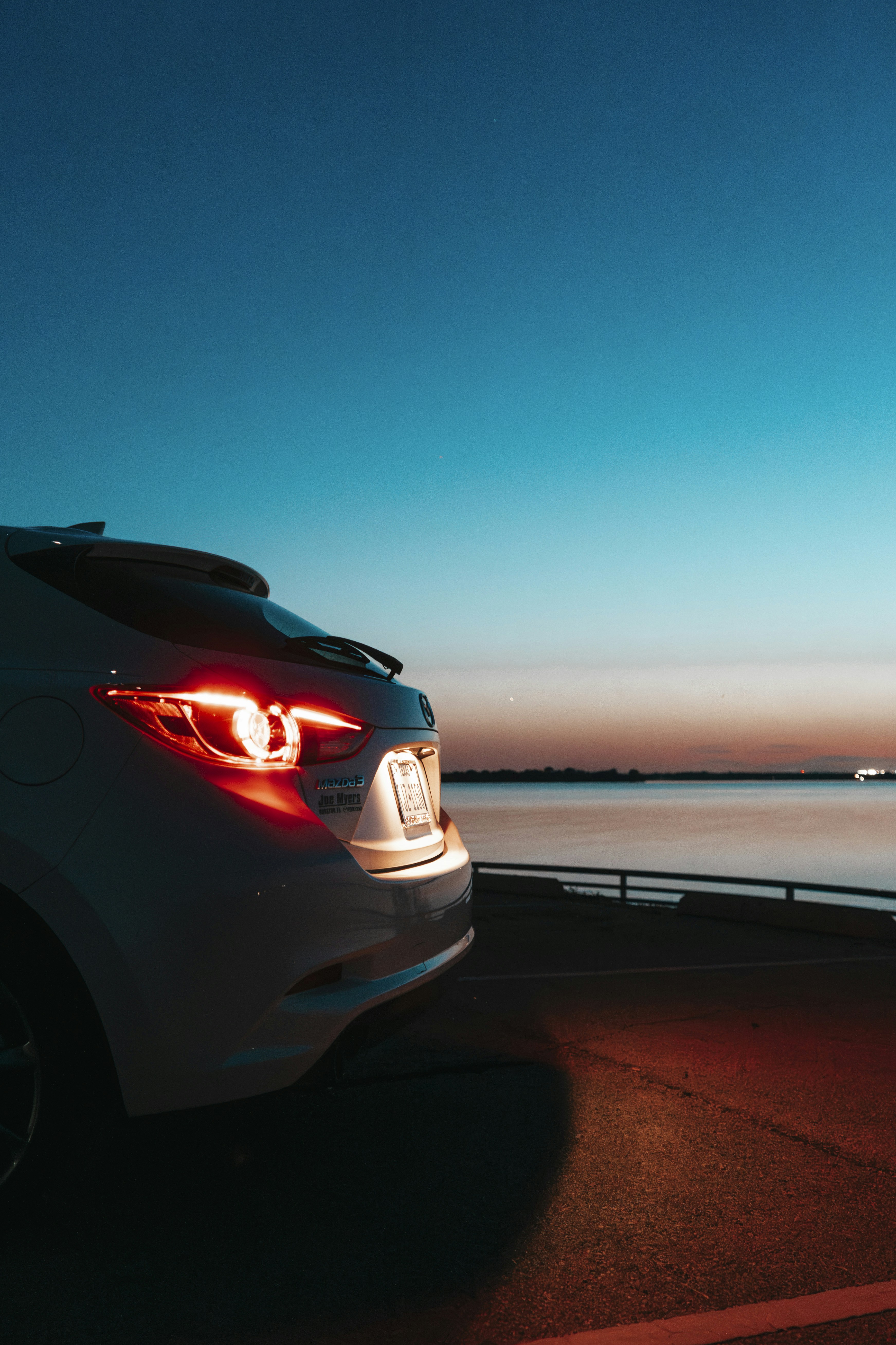 A white car parked next to a body of water