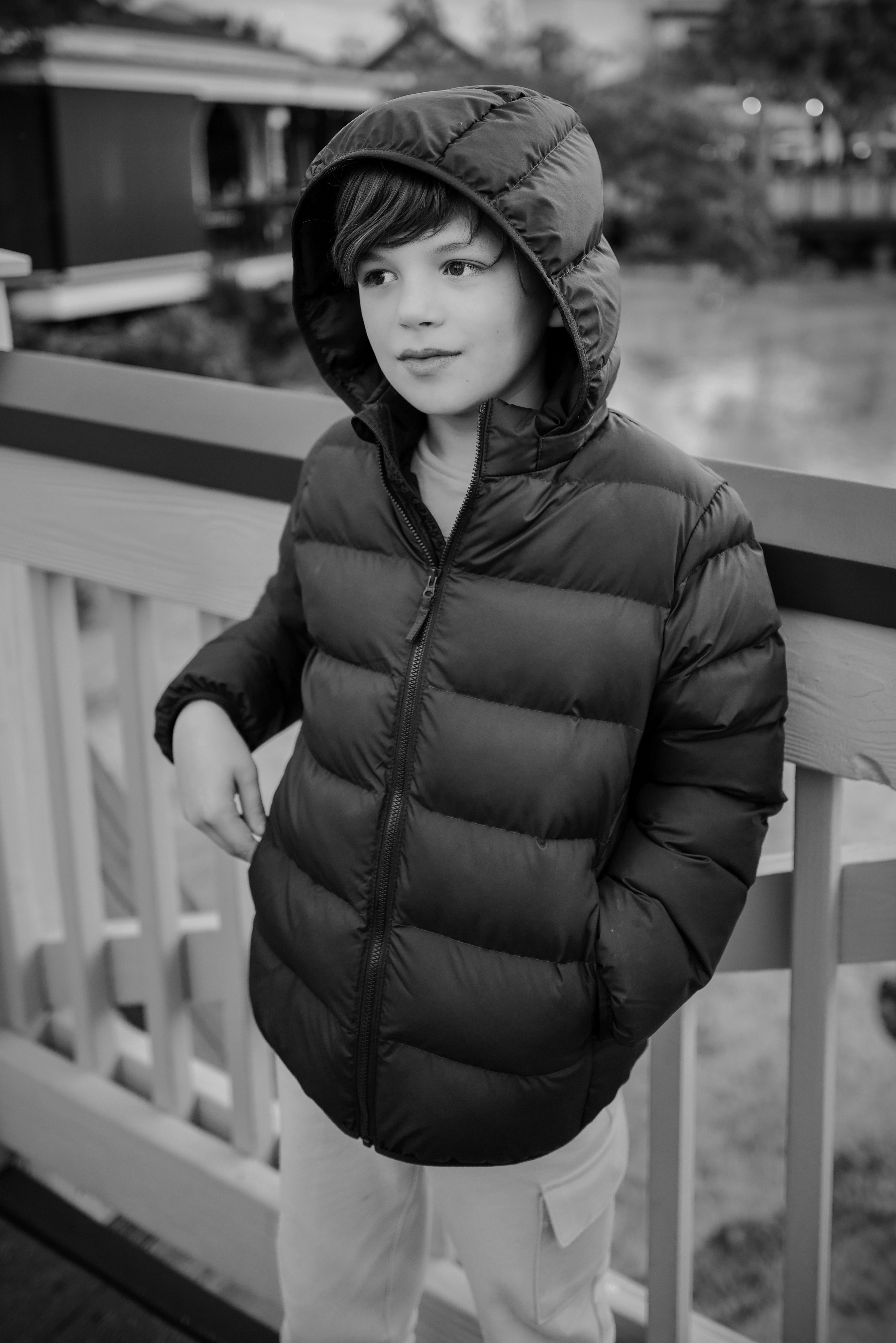 A young boy standing on a porch next to a fence