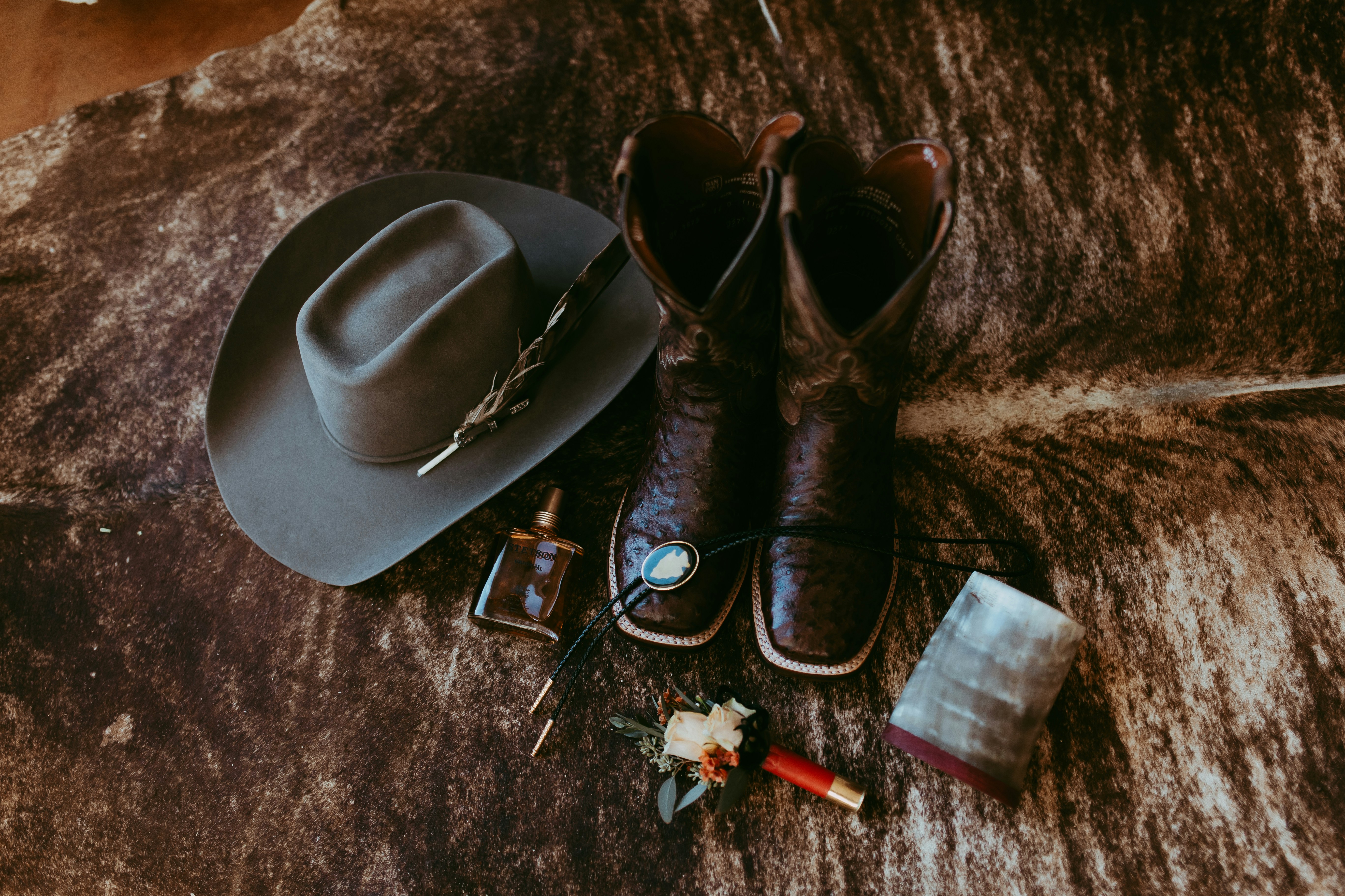 A pair of cowboy boots and a hat on a fur rug