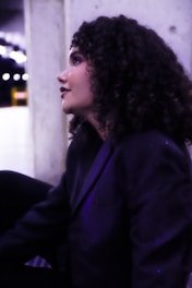 A woman with curly hair sitting on a bench