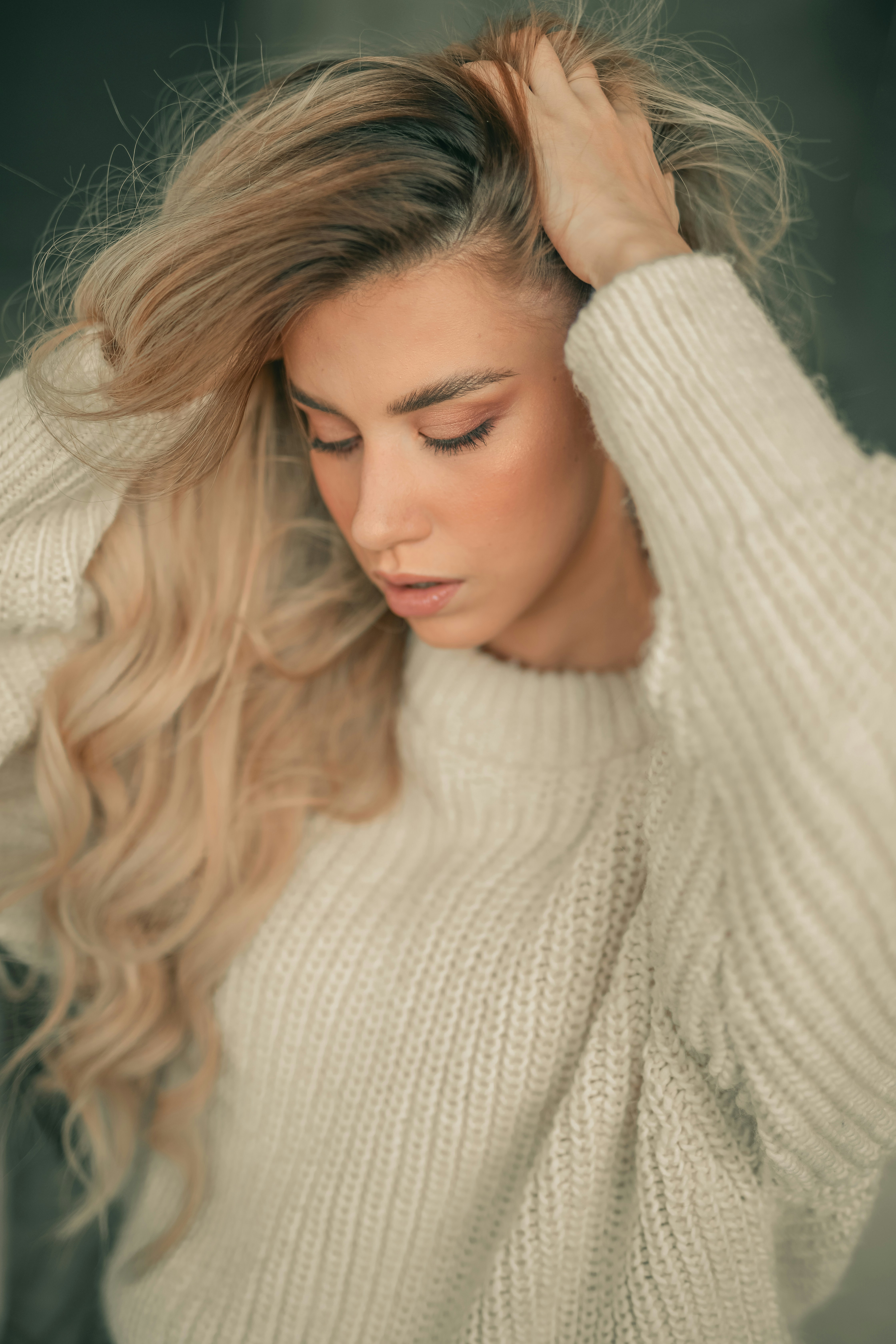 Una donna in un maglione bianco che si tiene i capelli