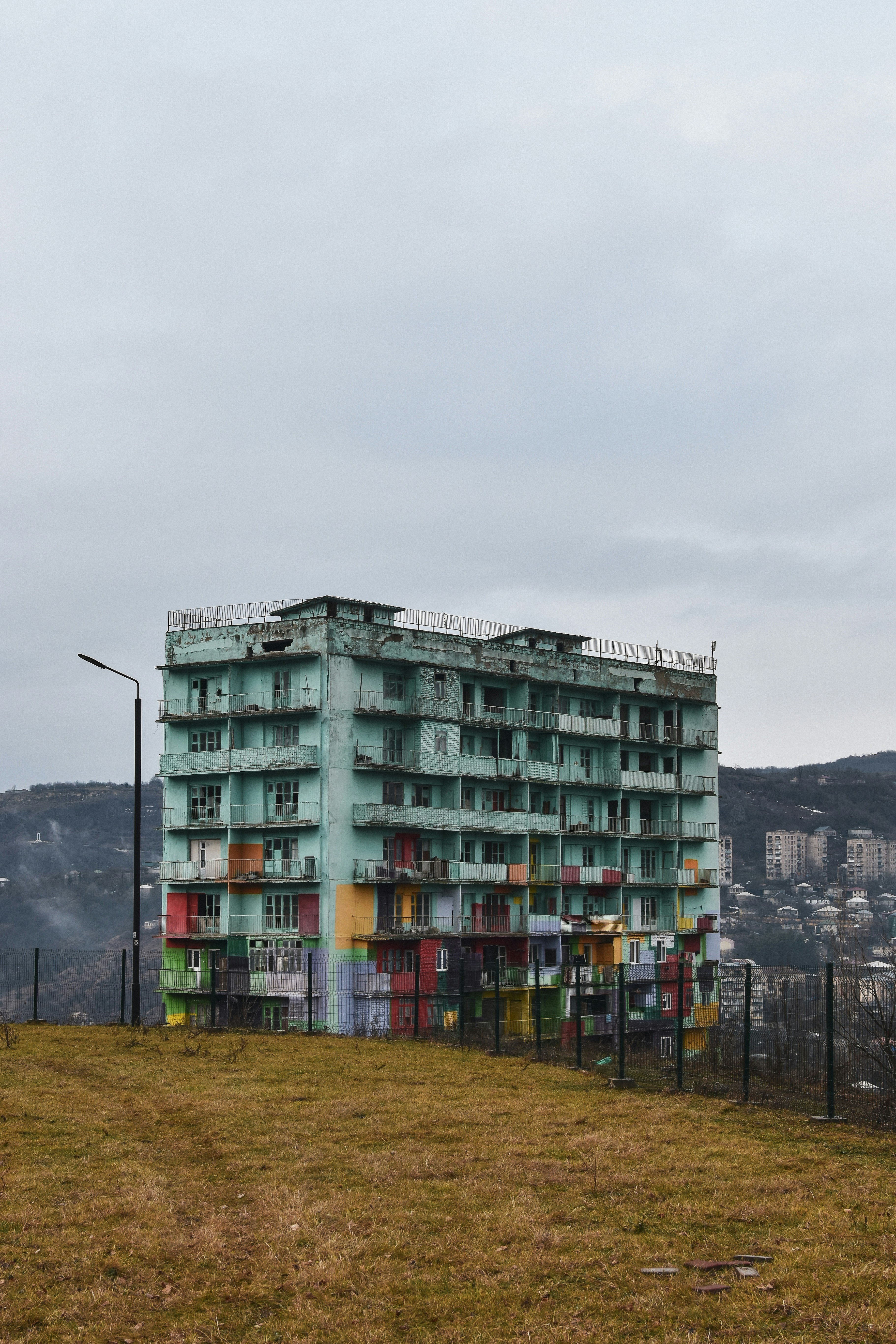 A tall building sitting on top of a grass covered hill