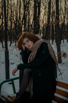 A woman sitting on a bench in the snow