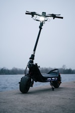 A scooter parked on the side of the road near a body of water