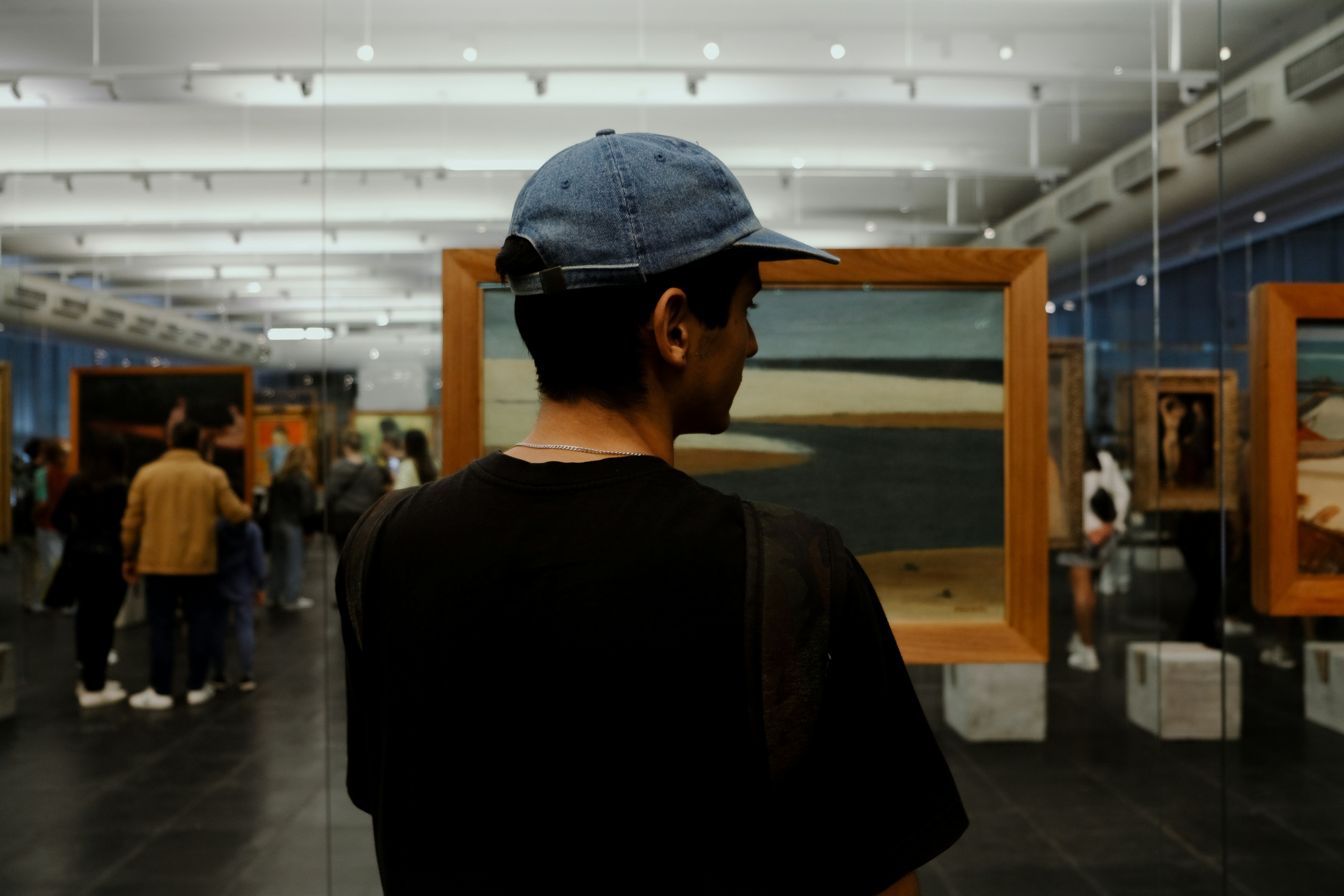 Un homme au chapeau bleu regardant des tableaux