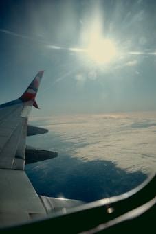 A view of the wing of an airplane as it flies over the clouds