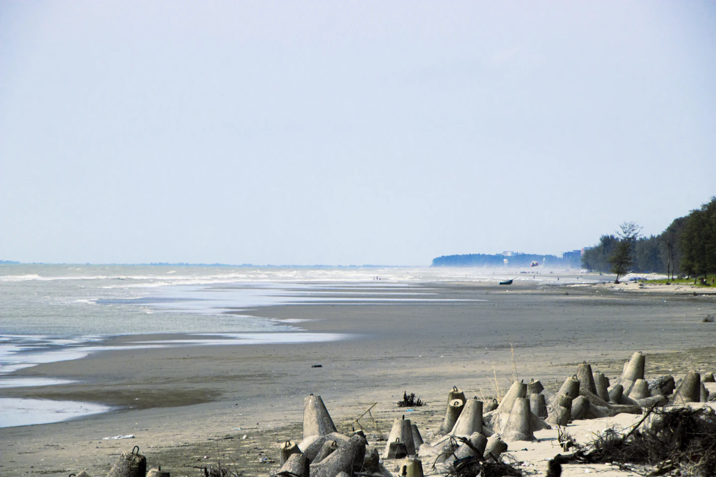 Waves rolling onto the wide, empty sand of Inani Beach under a blue sky