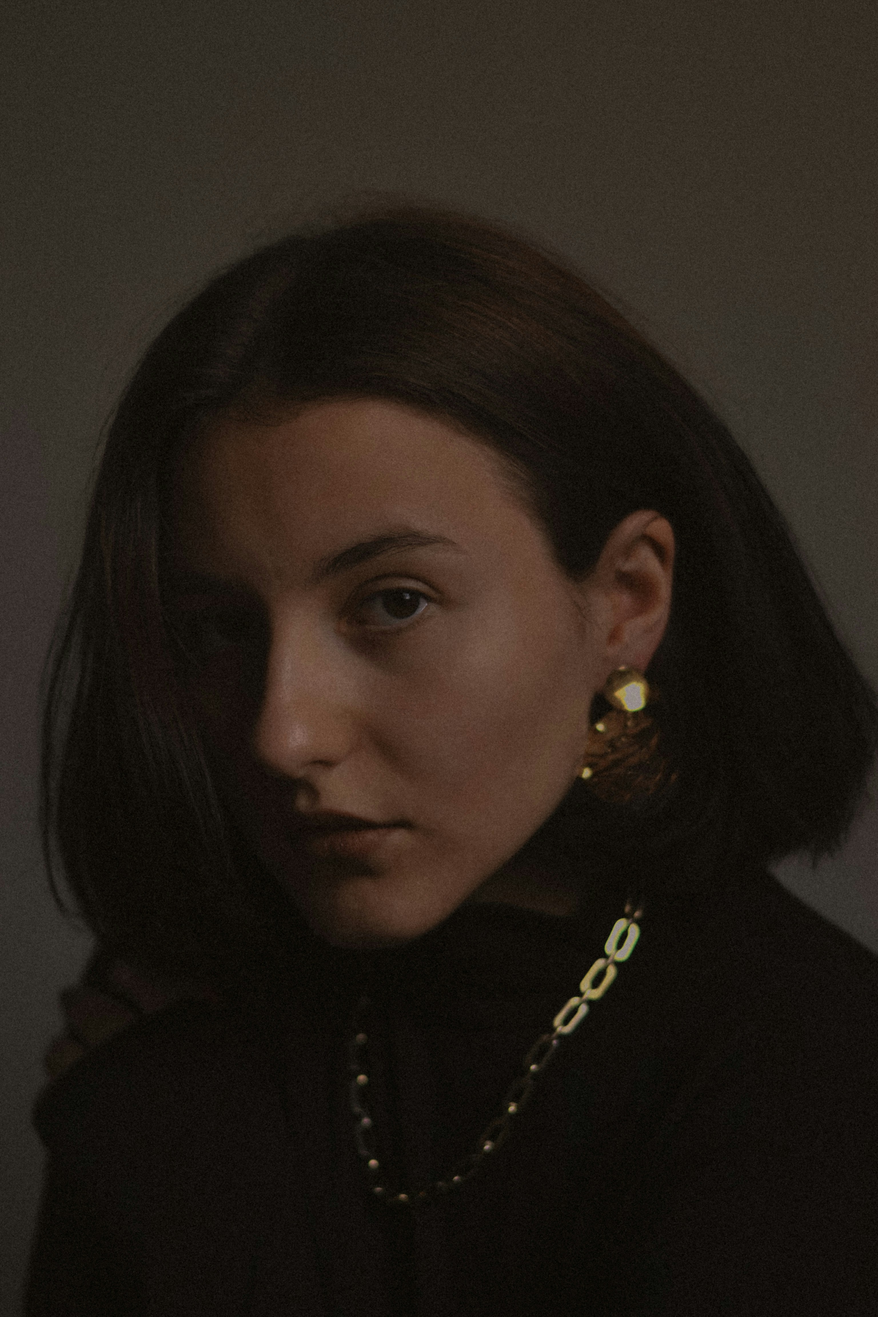 A woman wearing a black shirt and gold earrings