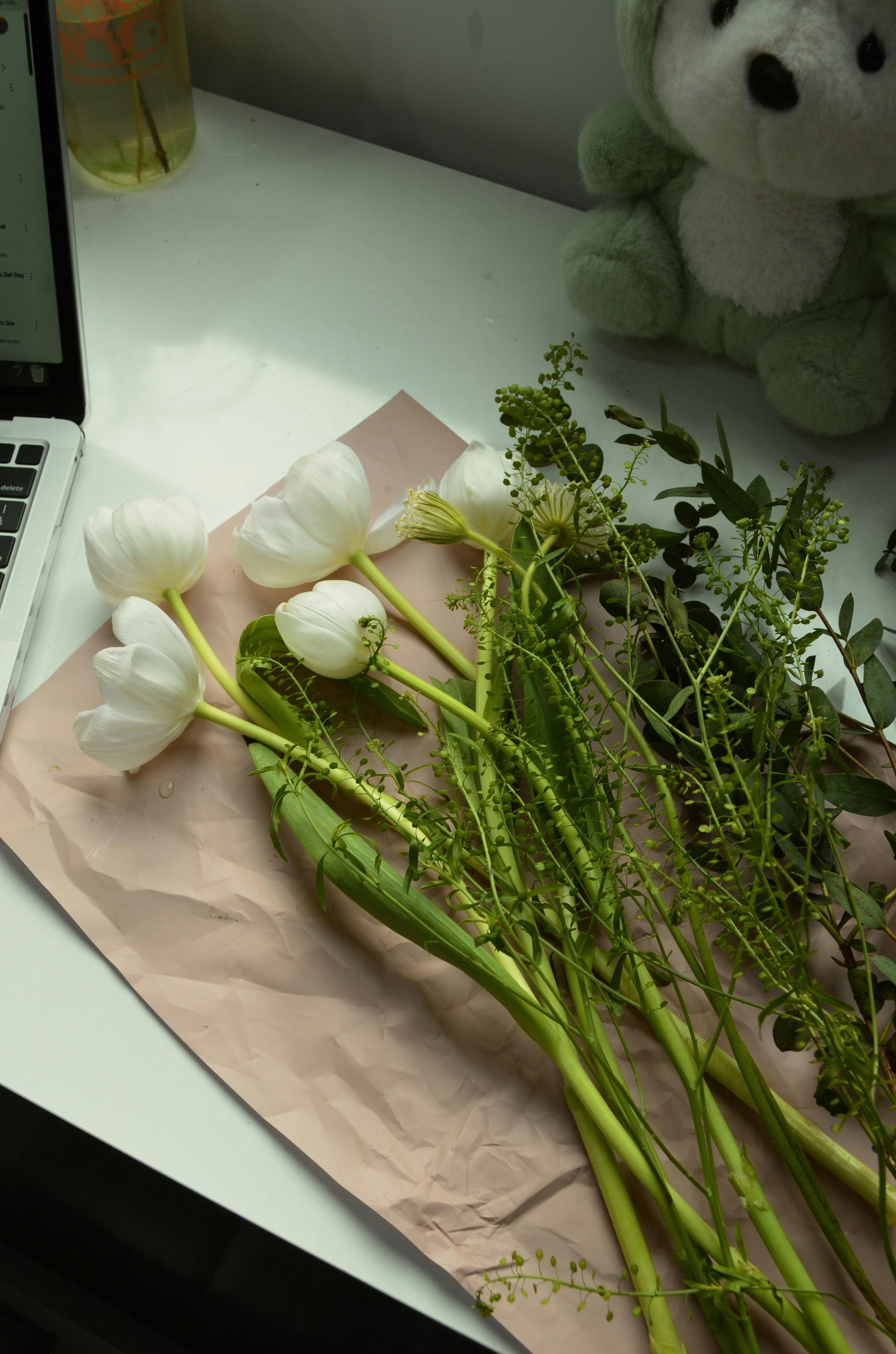 A laptop computer sitting on top of a desk next to a bunch of flowers