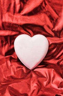 A white heart sitting on top of a red cloth