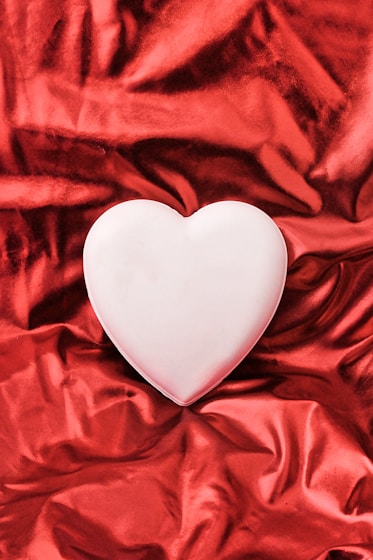 A white heart sitting on top of a red cloth